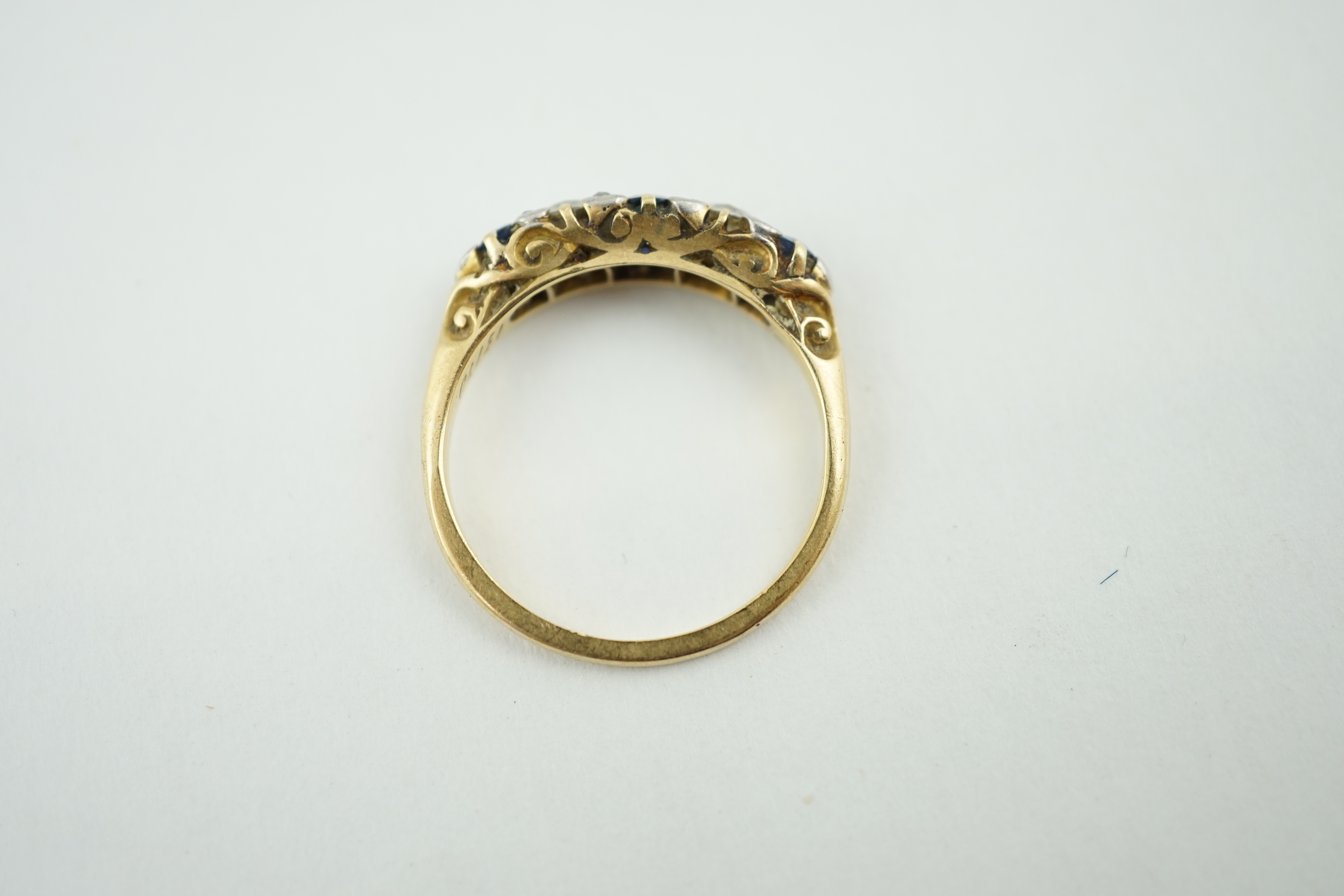 A gold, three stone sapphire and two stone diamond set half hoop ring